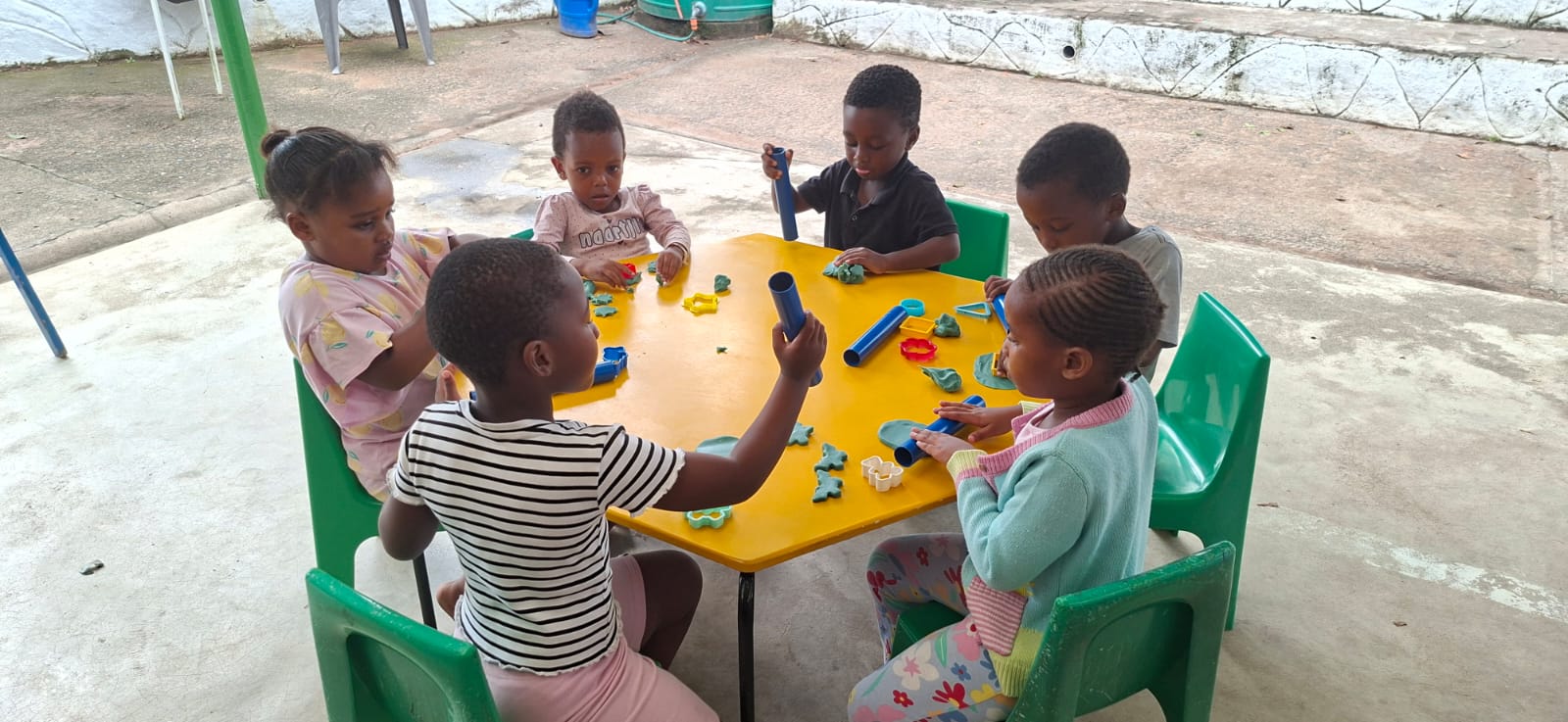 Young children enjoying playdough around a table