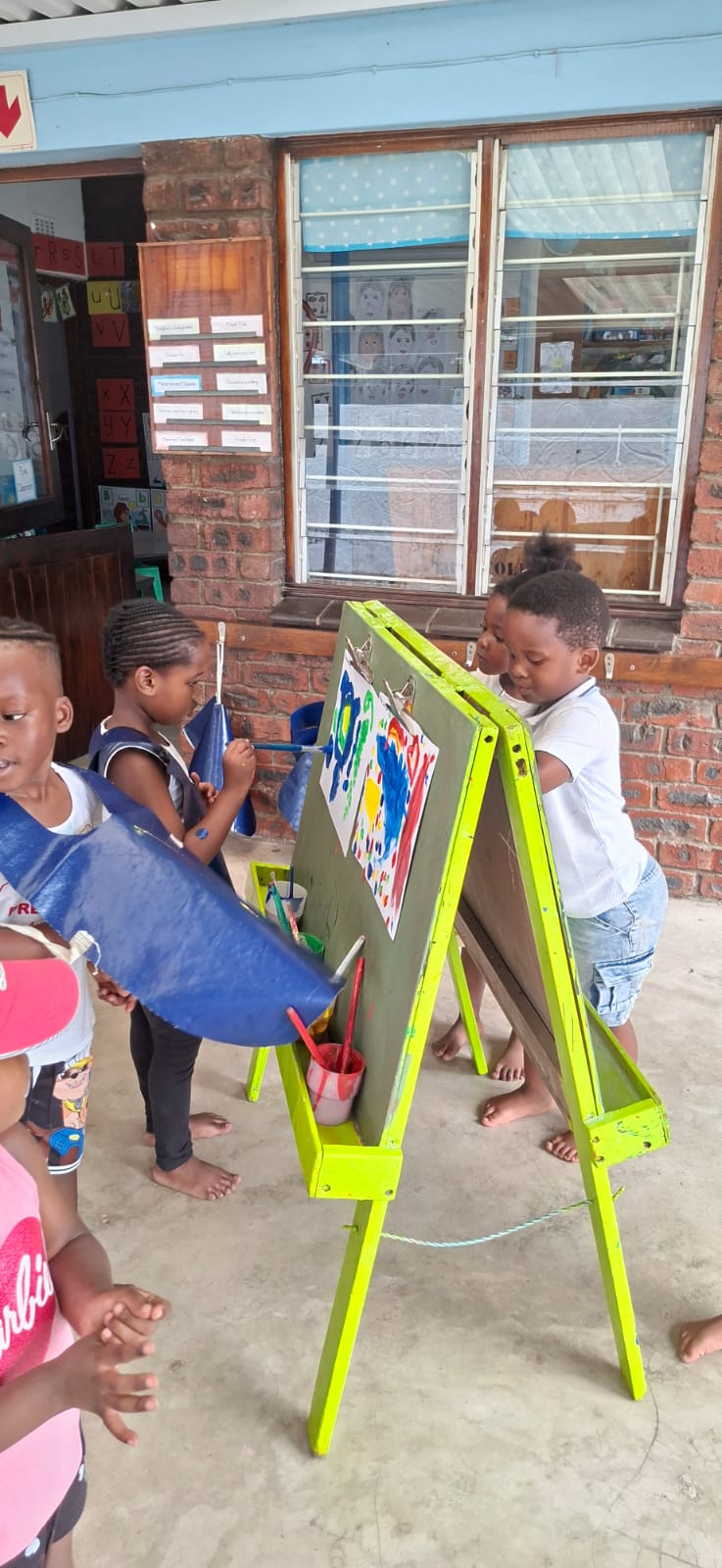 Children painting at an easel outside their classroom