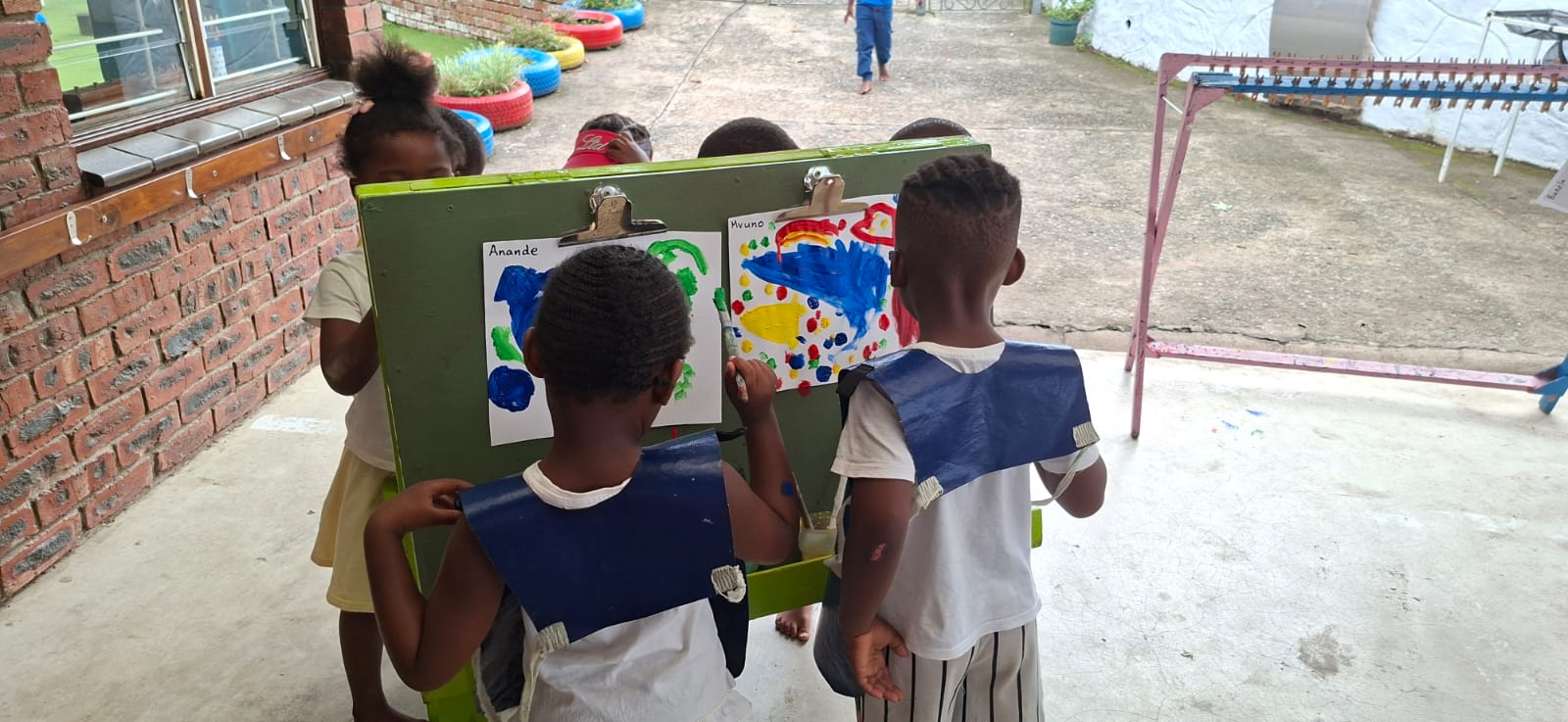 Children painting colourful pictures at an easel