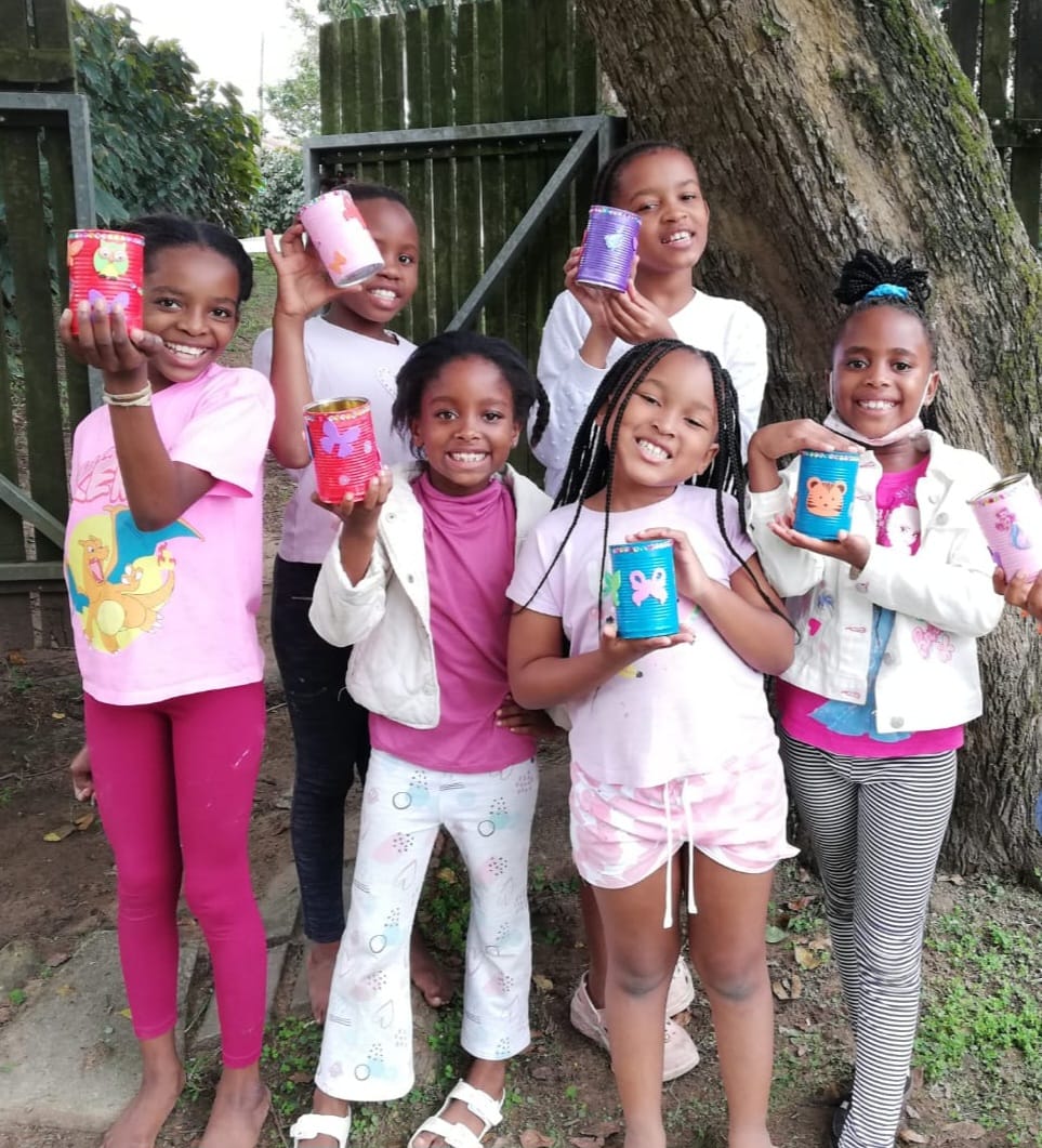 Children proudly showing their decorated craft tins