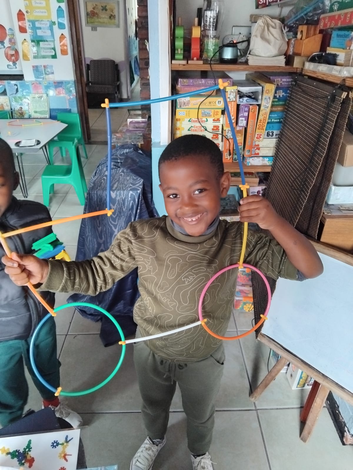 A child proudly showing a colourful construction made with connecting pieces